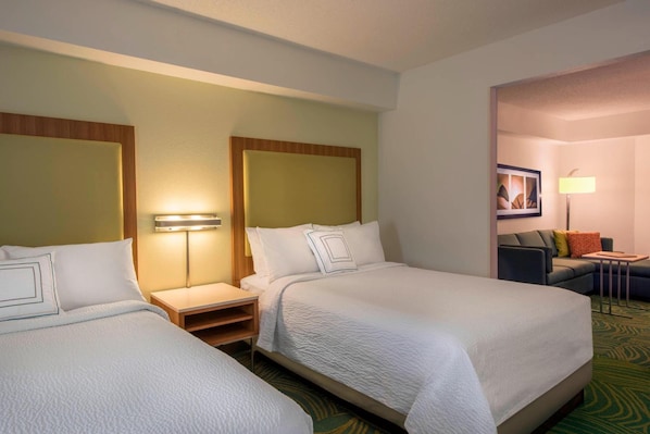 A hotel room with two beds, a nightstand, a lamp, a sofa, and a small table. - Springhill Suites by Marriott Charlotte Airport (Charlotte)