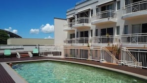 Ein Poolbereich mit klarem Wasser, umgeben von einer Holzterrasse.