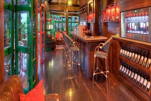A bar area with wooden flooring, bar stools, and a wine rack. - Nayara Gardens (San José)