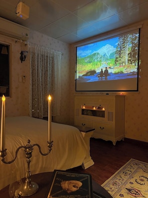 Ein Hotelzimmer mit einem Bett, einem an der Wand befestigten Fernseher, einer kleinen Kommode und einem dekorativen Teppich.