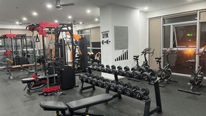 Un gimnasio con diversos equipos de ejercicio, como mancuernas, bancos y máquinas de pesas.