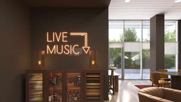 Ein modernes Wohnzimmer mit einem Neon-Schild mit der Aufschrift „LIVE MUSIC“, einer Holztruhe mit Flaschen und einer Ledersofa.