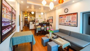 A hotel lobby with a dining area, a sofa, tables with tablecloths, and a 'Booking Office' sign. - The Linh Hoi An (Hoi An)