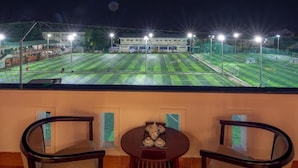 A balcony with a view of a sports field at night, equipped with a table and chairs. - The Linh Hoi An (Hoi An)