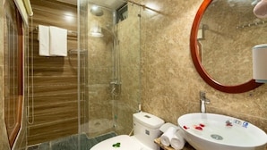 A modern bathroom with a glass-enclosed shower, a white toilet, and a large oval sink with a mirror above it. - The Linh Hoi An (Hoi An)