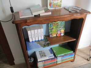 Een houten boekenkast met meerdere planken, vol met boeken en tijdschriften.