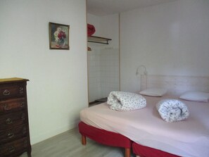 Een slaapkamer met een bed, een dressoir, een douche en een klein schilderij aan de muur.