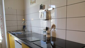 Uma cozinha com bancada preta, pia e suporte para utensílios.