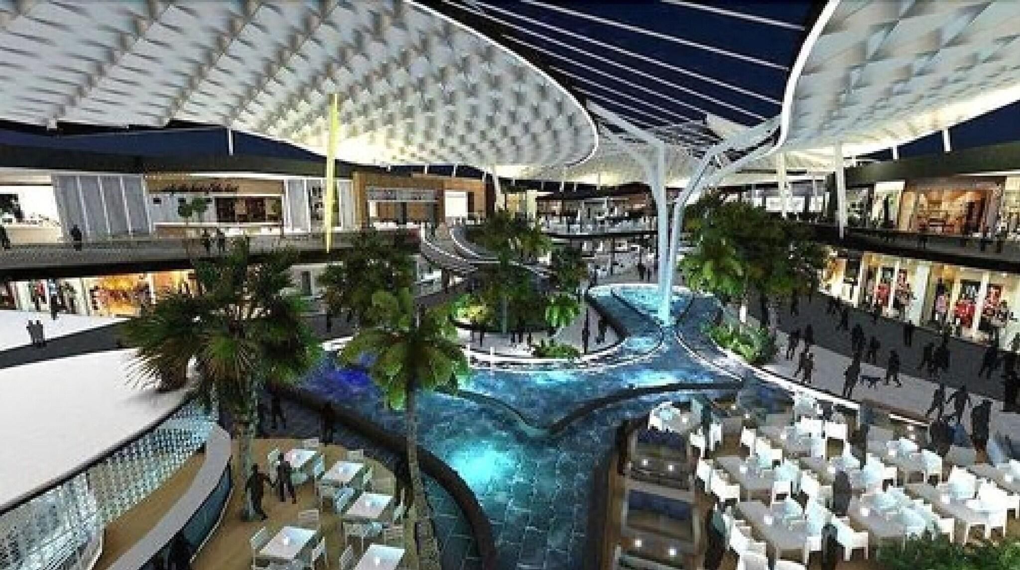A multi-level indoor space with a central water feature, surrounded by seating areas and greenery.