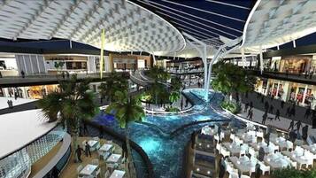 A multi-level indoor space with a central water feature, surrounded by seating areas and greenery.