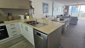 Una cocina moderna con lavavajillas, un lavamanos y una zona de comedor con mesa y sillas.