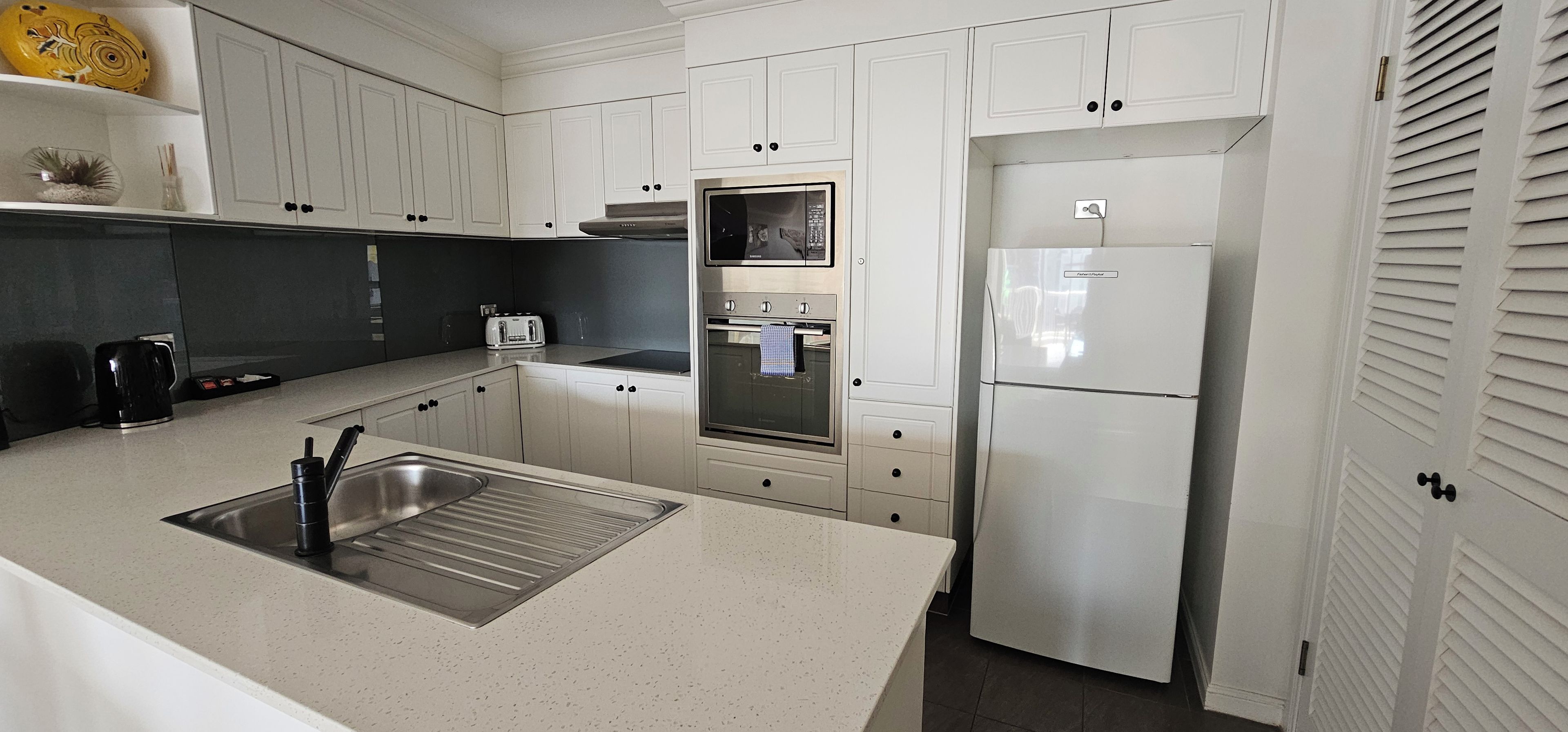 A modern kitchen with white cabinets, stainless steel appliances, and a black countertop.