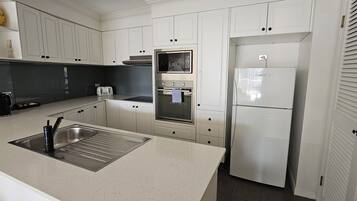 A modern kitchen with white cabinets, stainless steel appliances, and a black countertop.