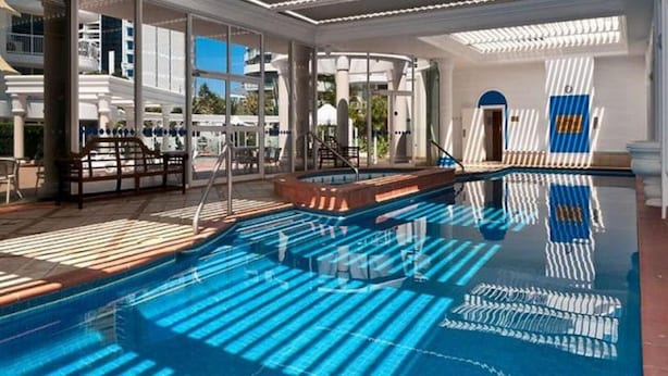 Un área de piscina con paredes de vidrio transparente, una piscina y un tragaluz.