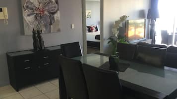 Un comedor moderno con una mesa de vidrio, sillas negras, un jarrón con flores y un cuadro en la pared.