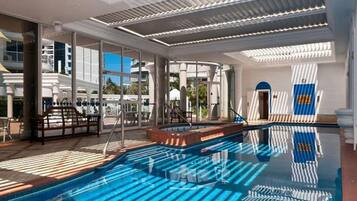 Un área de piscina con paredes de vidrio transparente, una piscina y un tragaluz.