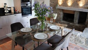 Una cocina moderna con una mesa de vidrio, sillas y una chimenea de piedra.