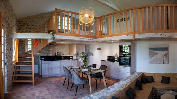 Una cocina amplia con comedor, escalera de madera y vista al mar.