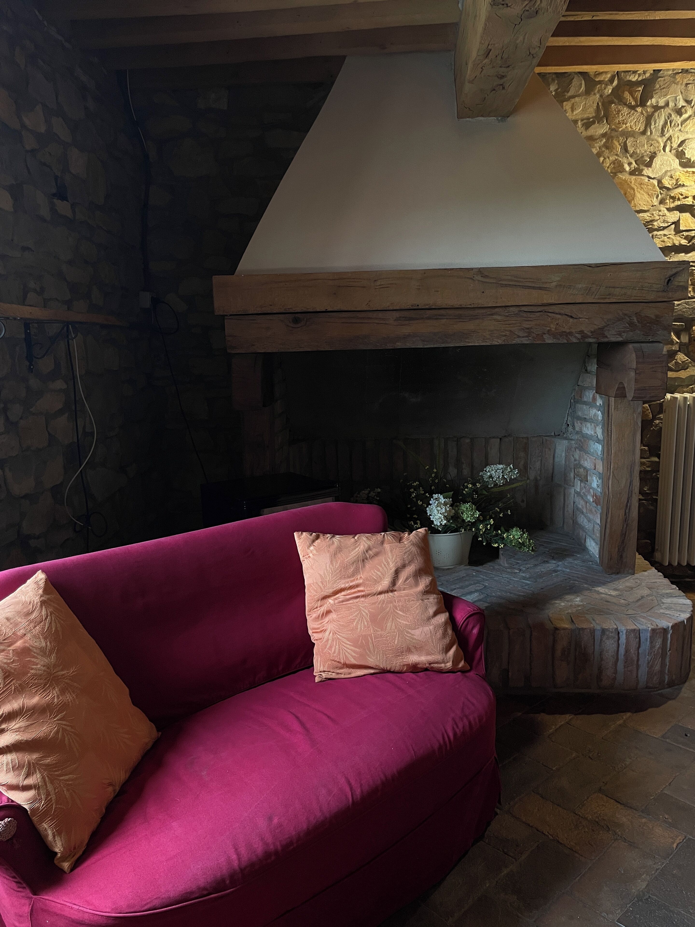 A cozy room with a stone wall, a wooden ceiling, and a fireplace.