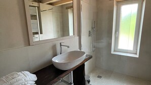 A bathroom with a white sink, a large mirror, and a shower.
