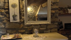 A stone wall with a framed mirror, a potted plant, and a white dresser with drawers.