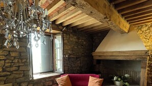 A cozy room with a stone wall, a red sofa, a white table, and a chandelier.