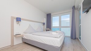 Een moderne hotelkamer met een bed, nachtkastjes, een raam met uitzicht en een balkon.