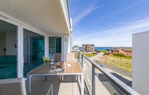 A balcony with a table set for dining, a view of the sea, and a residential area in the background. - Stunning apartment in Kappeln with sauna (Kappeln)