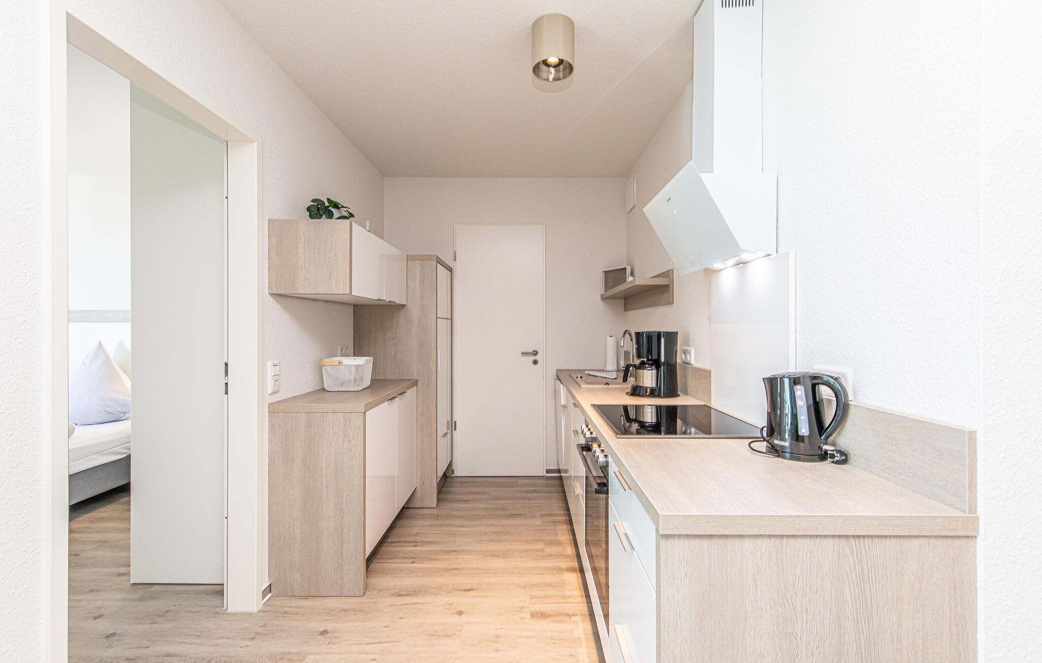 Une cuisine moderne avec des meubles en bois, une cuisinière encastrée et une machine à café.