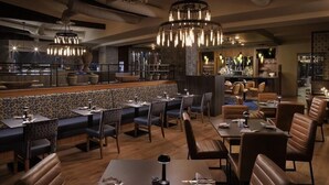 Un restaurante con cabinas y mesas, una zona de bar y una pared con diseño.