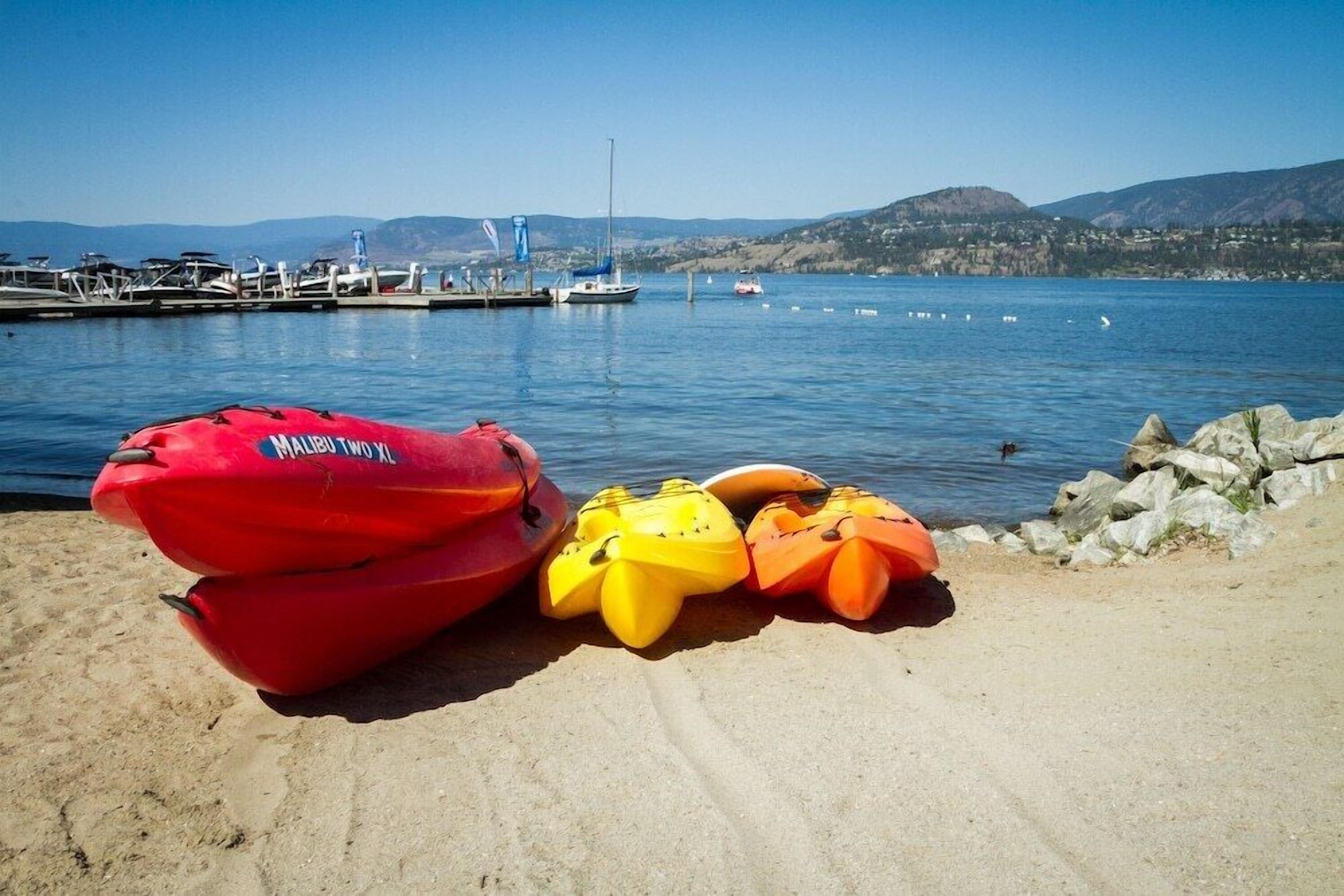 Una spiaggia sabbiosa con diversi kayak e un'imbarcazione gonfiabile rossa vicino alla riva.