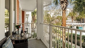 Un balcon avec une table, des chaises et une bouteille de vin.