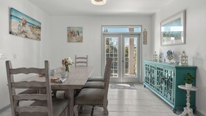 Et spiseområde med et træbord og stole, et skab i turkis og billedkunst på væggene.