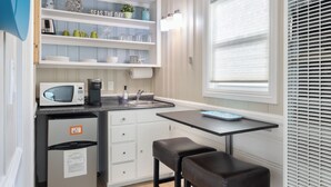 A compact kitchen with a microwave, coffee maker, and a small dining table with two stools. - Bayfront Studio, Walk to Beach & Shops | Edgewater (Newport Beach)