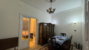 Ruokailuhuone, jossa on neljälle katettu ruokapöytä, penkki, kaappi ja kuviollinen matto.