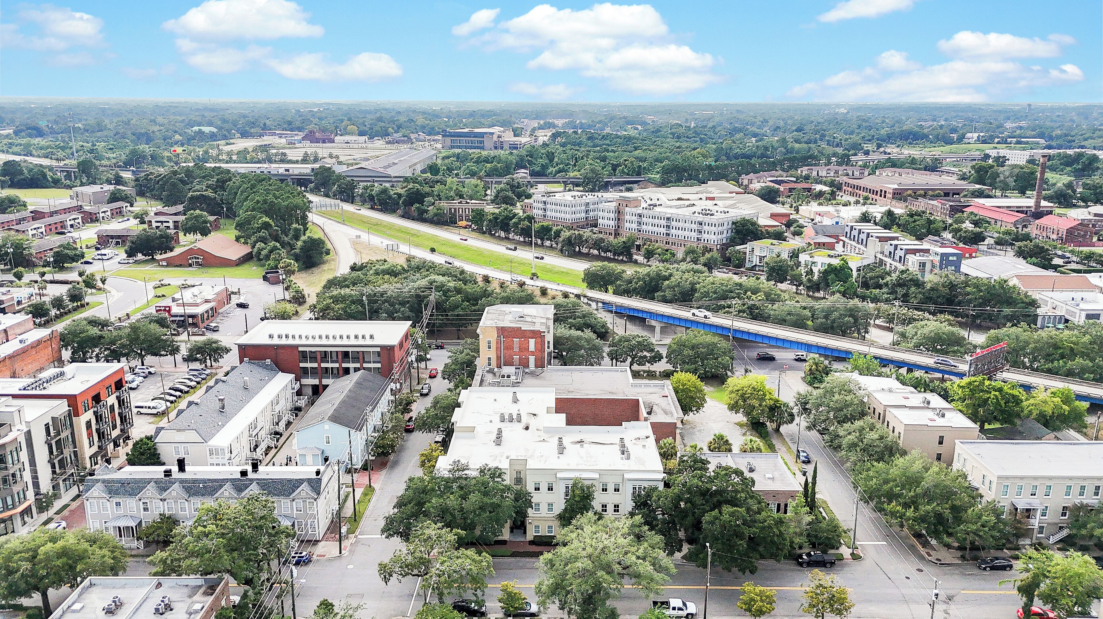 An aerial view of a cityscape with various buildings, roads, and greenery.