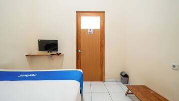 A room with a bed, a bench, a television on a stand, and a door.