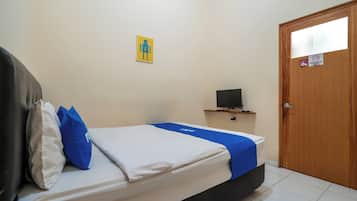 Habitación de hotel con una cama, un televisor sobre un soporte, una puerta de madera y una obra de arte colgada en la pared.