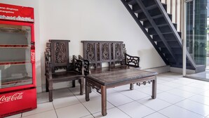 Ein Zimmer mit einer Coca-Cola-Automaten, zwei Holzstühlen, einem Tisch und einer Treppe.