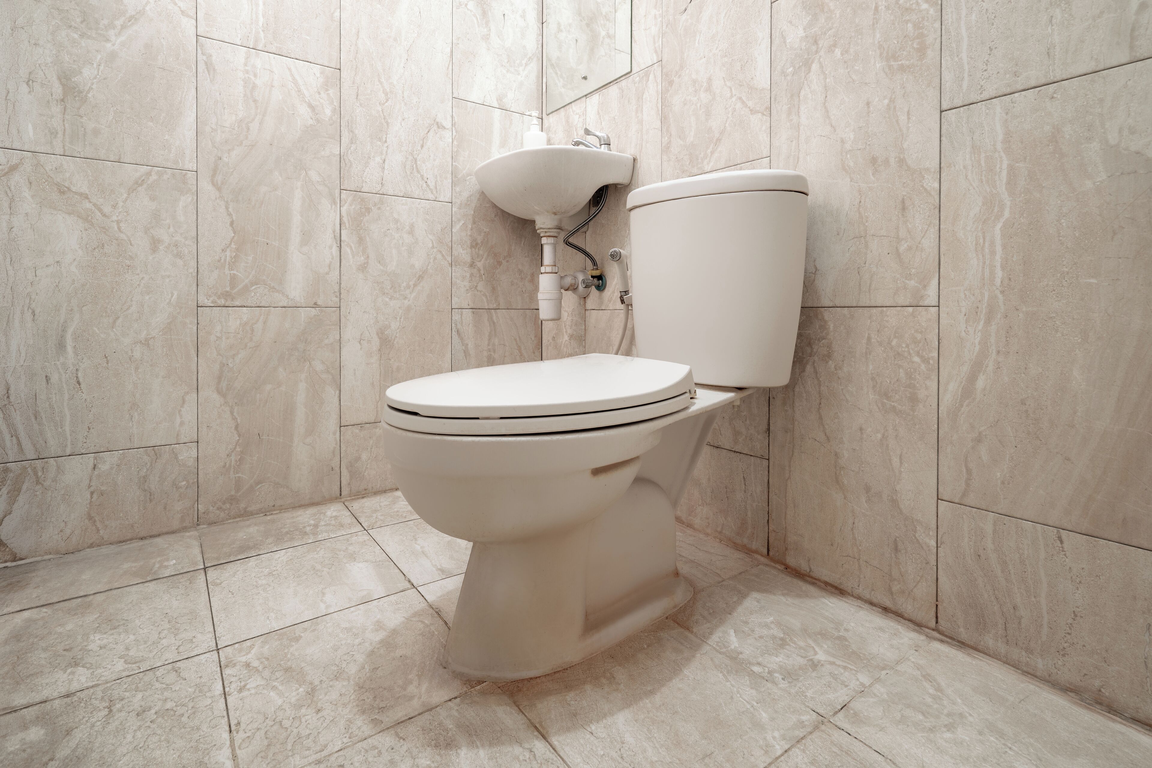 A bathroom with a toilet, sink, and tiled walls.