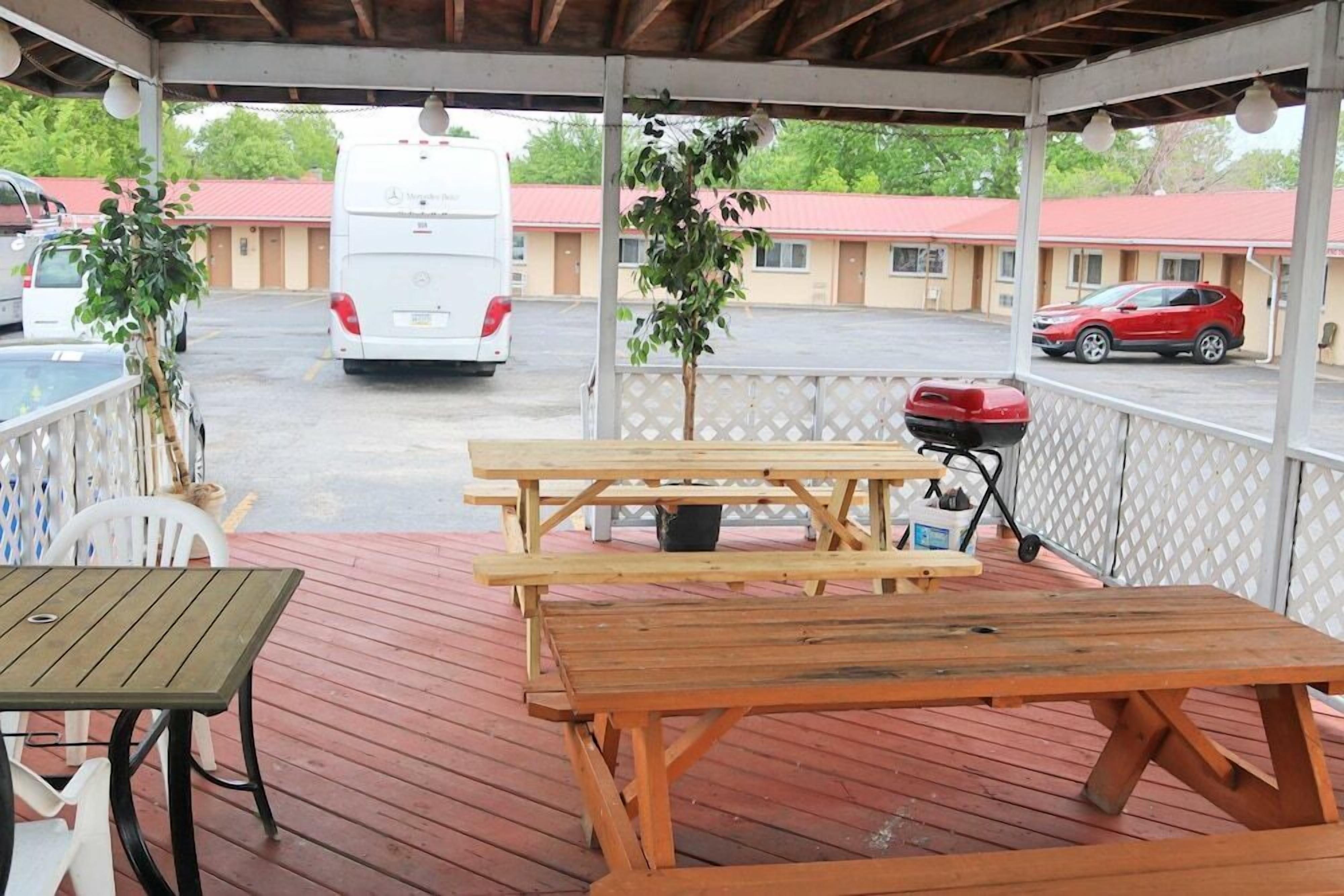 A covered outdoor area with picnic tables and a barbecue grill.