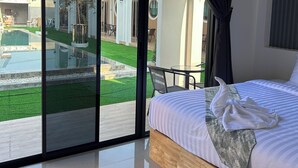 Une chambre d’hôtel dotée d’une grande porte-fenêtre coulissante donnant sur une piscine et un jardin.