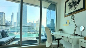 A modern office with a large window overlooking a cityscape and water. - Fully Furnished 2 Bed in Dubai Marina. (Dubai)
