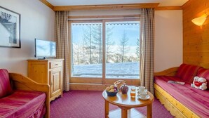 Una habitación acogedora con una cama, un armario de madera, una mesa con productos para el desayuno y una ventana con vistas nevadas.