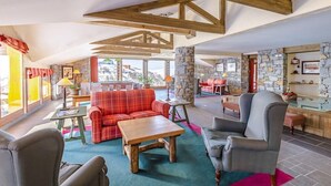 A spacious living area with a wooden ceiling, a stone fireplace, and a view of the outdoors. - Lagrange Prestige Aspen - La Plagne (La Plagne-Tarentaise)