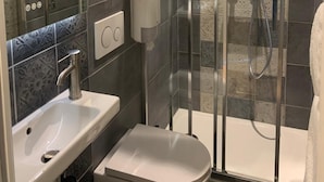 A modern bathroom with a glass-enclosed shower, a white sink, and a toilet. - Laugeval (Deauville)