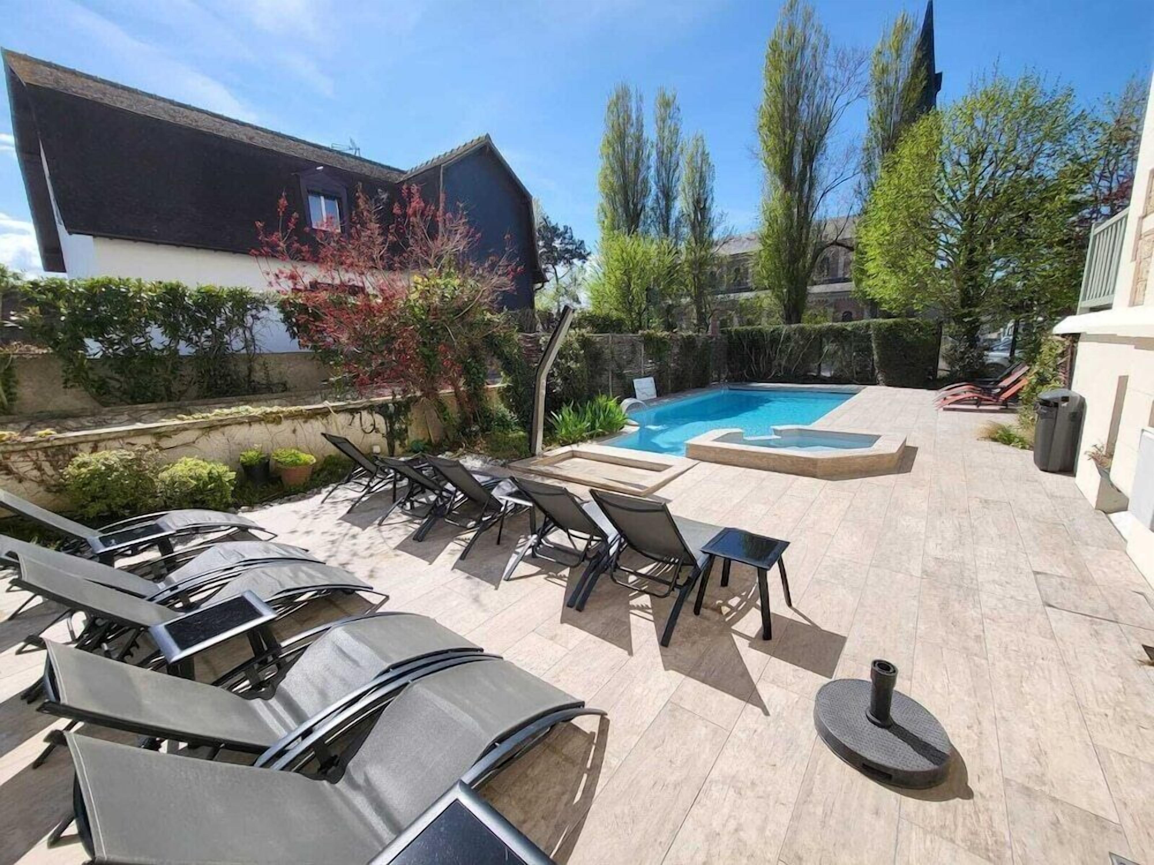 A pool area with lounge chairs and a hot tub.