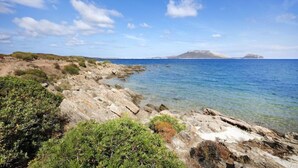 Línia de costa rocosa amb aigües blaves cristal·lines i paisatges llunyans.
