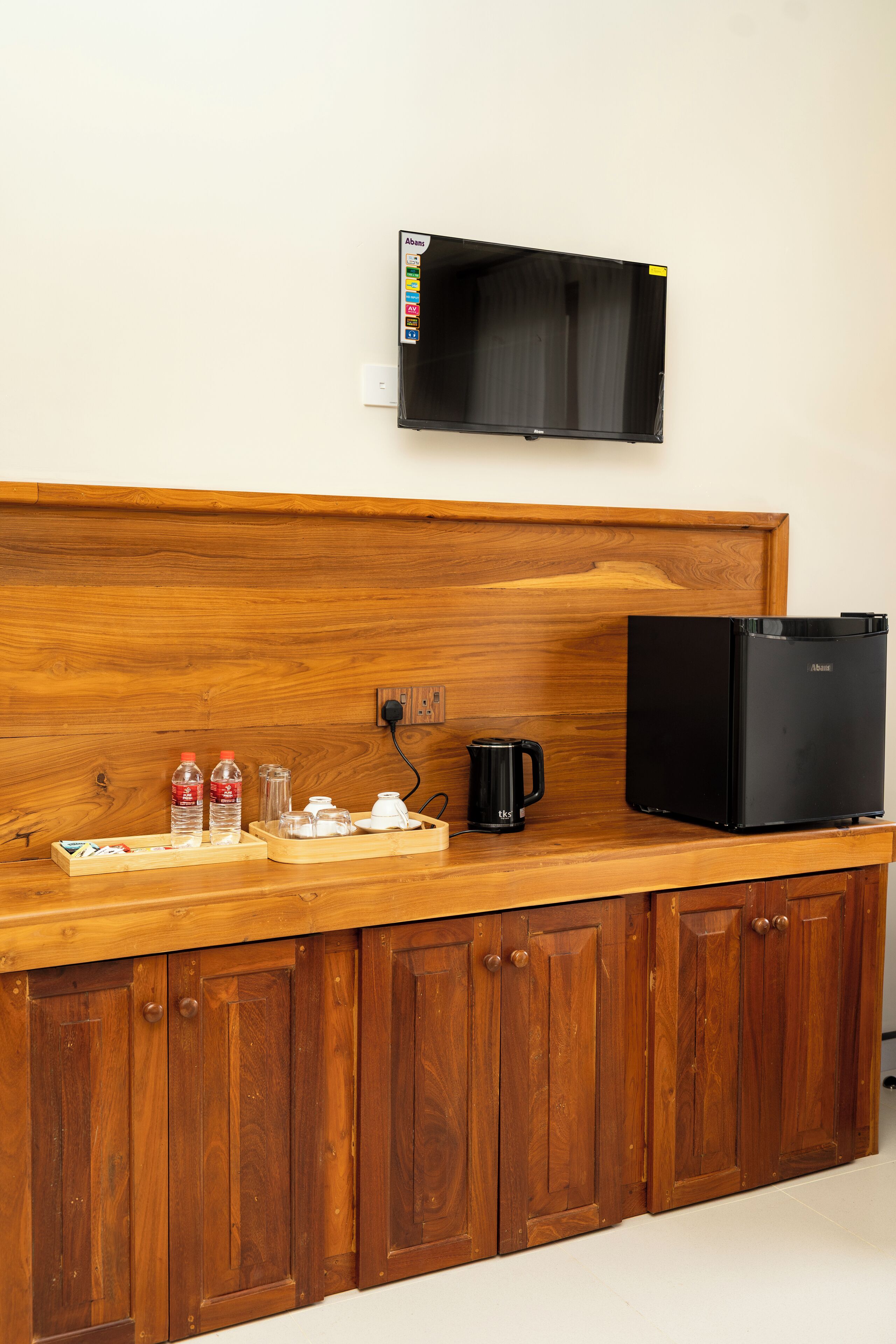 Una kitchenette con microondas, cafetera y botellas de agua sobre una encimera de madera.