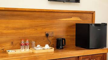 Una kitchenette con microondas, cafetera y botellas de agua sobre una encimera de madera.